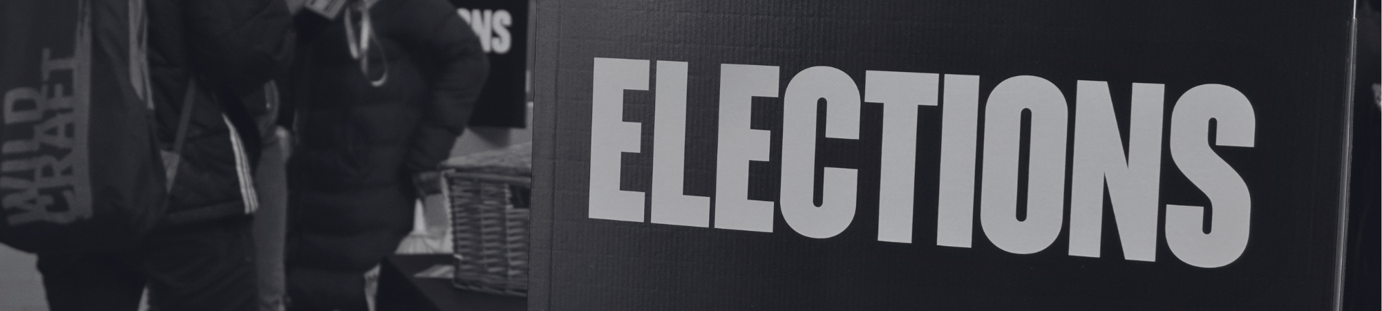 A sign that states 'Elections' in white font with a student voting in the background