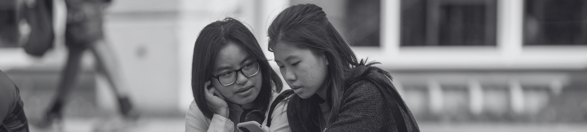 Two students sitting together looking at a phone