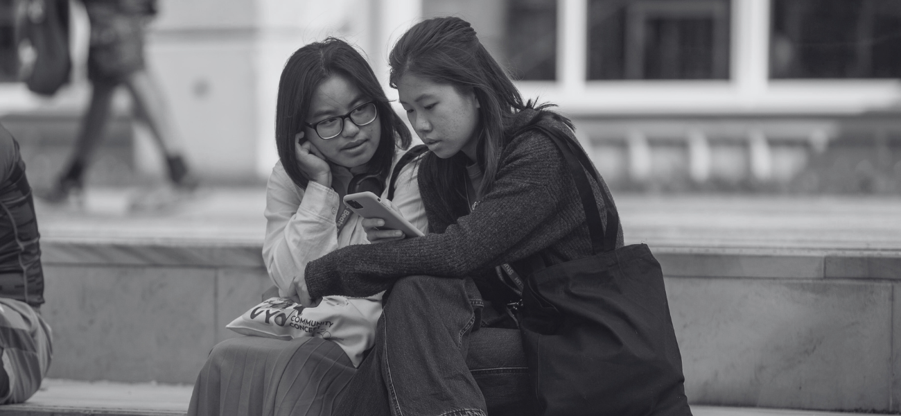 Two students sitting together looking at a phone