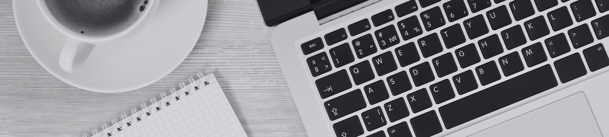 Coffee, notepad and a laptop on a desk