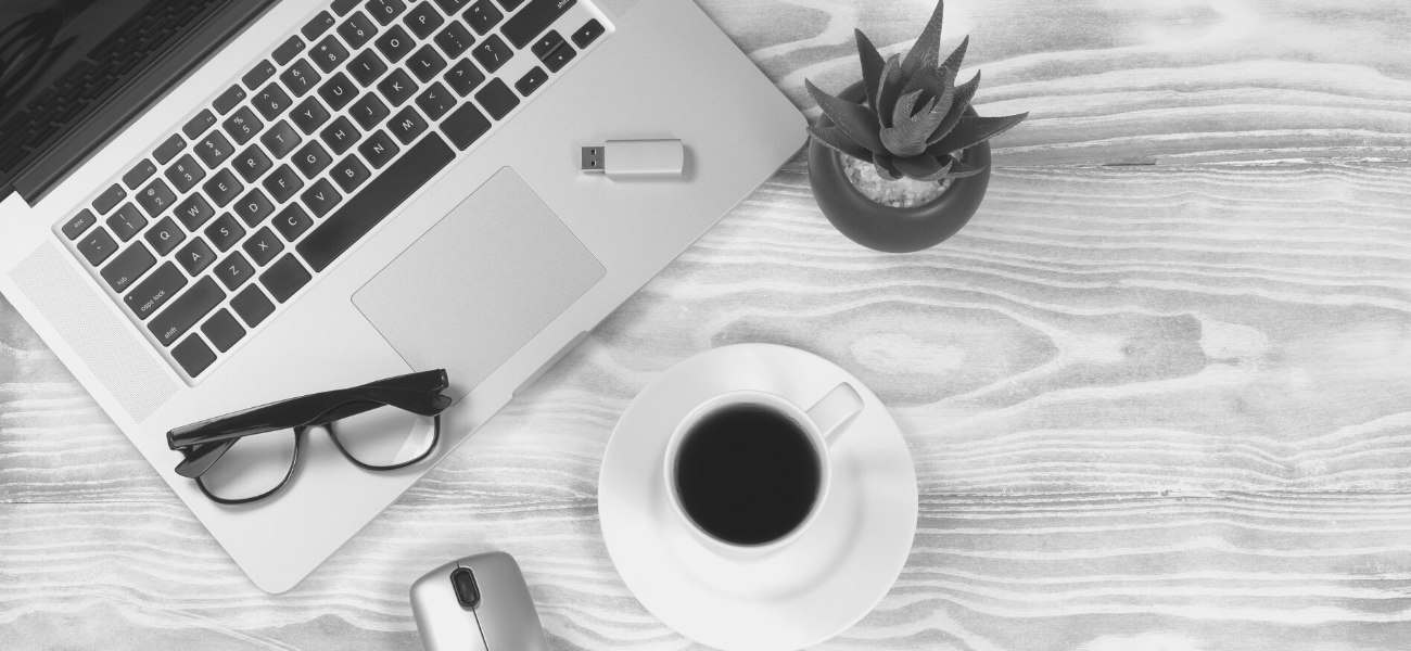 Laptop, coffee, plant, and glasses on a table top